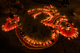 Das spirituelle hinduistische Om-Zeichen wird zu Diwali in Varanasi mit Kerzen beleuchtet
